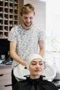 Hairdresser wrapping towel on customer`s head. Brunette woman getting hair treatment in a salon.