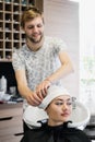 Hairdresser wrapping towel on customer`s head. Brunette woman getting hair treatment in a salon.