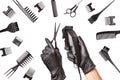 Hairdressers hands in black rubber gloves holds hair clipper and scissors surrounded by professional hairdressing accessories