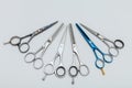 Hairdressing equipment like different scissors on gray wooden table in professional salon with copy place