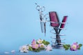 Hairdressing tools on a metal stand decorated with delicate pink flowers on a blue background