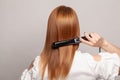 Hairdressing. Woman with beautiful long healthy hair using hair straightener Royalty Free Stock Photo