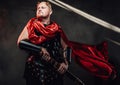 Hairless roman warrior pose with red cape in dark background