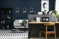 Hairpin desk with books, laptop and lamp in dark industrial living room interior with decor on metal rack, carpet and three clock Royalty Free Stock Photo