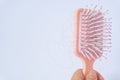 Hair loss problems with hand holding a pink hairbrush on white background. Falling black hair clinging to the comb
