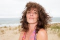 Hairs on wind middle aged woman sitting on beach smiling in summer Royalty Free Stock Photo