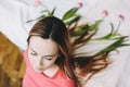 Hairstyle with flowers. Romantic portrait of a girl in bed with natural flowers. Young woman with tulips in hair. Beautiful photo Royalty Free Stock Photo