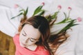 Hairstyle with flowers. Romantic portrait of a girl in bed with natural flowers. Young woman with tulips in hair. Beautiful photo