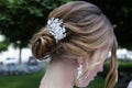 Hairstyle of a young beautiful blonde woman with a beautiful white hair clip of beads in her hair styled.