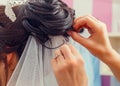 Hairstyling process. Beautiful wedding hairstyle. Hairdresser master making curls. Rear view of stylish close-up hairdress of the