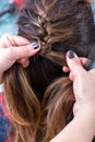 Hairstylist braiding the brown hair of a woman