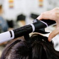 Hairstylist curling hair close up. Hairdresser making hairstyle to brown long hair woman in beauty salon. Professional hair care, Royalty Free Stock Photo