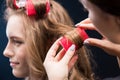 Hairstylist curling hair of woman