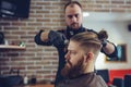 Hairstylist cutting hair of male customer at barber shop.