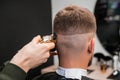 Hairstylist shaves male occiput with trimmer in barbershop