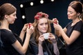 Hairstylists curling hair to woman