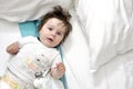 Hairy baby in bed with two pillows