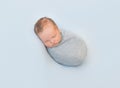 Hairy infant sleeping curled, wrapped in gray blanket Royalty Free Stock Photo