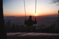 Hairy young boy aged 16-20 of European descent enjoys his life swinging on a swing at sunset on the top of Prasiva mountain in the