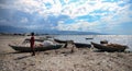 Haiti - March, 2017: A young girl stands on a polluted beach in Haiti surrounded by old fish boats and garbage