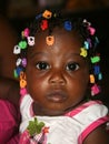 Haitian infant adorned with colorful barrettes in rural Haiti.