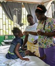 Haitian nurse cares for young patient as mother looks on.