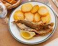 Fried hake served with boiled potatoes and lemon