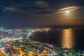 Hakodate City night view from Mt. Hakodate observatory, big bright moon light up the sea, golden reflection on surface Royalty Free Stock Photo