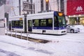Modern and electric trams run in urban and heavy snowfall.