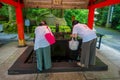 HAKONE, JAPAN - JULY 02, 2017: Unidentified people drinking water at the enter of red Tori Gate at Fushimi Inari Shrine in Kyoto, Royalty Free Stock Photo