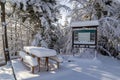 Rest area with table and benches and tourist information board, winter, Hala Slowianka, Poland