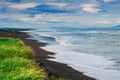 Halaktyr beach. Kamchatka. Russian federation. Dark almost black color sand beach of Pacific ocean. Stone mountains and Royalty Free Stock Photo