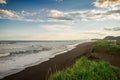 Halaktyr beach. Kamchatka. Russian federation. Dark almost black color sand beach of Pacific ocean. Stone mountains and yellow gra Royalty Free Stock Photo