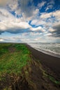 Halaktyr beach. Kamchatka. Russian federation. Dark almost black color sand beach of Pacific ocean. Stone mountains and yellow gra Royalty Free Stock Photo