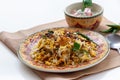 Halal Indian chicken Biryani served with yogurt tomato raita over white background. Selective focus.