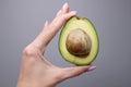 Half of avocado in human hand on gray background Royalty Free Stock Photo