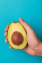Half of avocado with kernel in female hand Royalty Free Stock Photo
