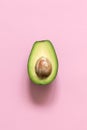 Half avocado on pastel pink background. Minimalism