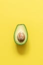 Half avocado on pastel yellow background. Minimalism