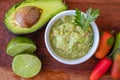 Half an avocado, some hot peppers and a lime on a wooden board and bowl with the guacamole sauce. Chopped or top view Royalty Free Stock Photo