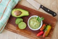Half an avocado, some hot peppers and a lime on a wooden board and bowl with the guacamole sauce. Chopped or top view Royalty Free Stock Photo
