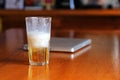 Half of beer in glass after drink on wooden table. Royalty Free Stock Photo