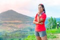 Half-body photo of a female trail runner wearing pink runner, sportswear, smiling, looking at the camera. on the gravel ground on