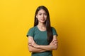 Half body shot beauty asian confidence teenager in green tee shirt folded arms and smiling stand isolated on yellow background.