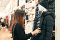 Half body shot of a happy asian young woman with shoulder bag looking at clothes hanging on the rail inside the clothing shop. Royalty Free Stock Photo