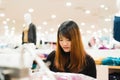 Half body shot of a happy asian young woman with shoulder bag looking at clothes hanging on the rail inside the clothing shop. Royalty Free Stock Photo