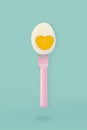 Half boiled egg on a pink fork on blue background