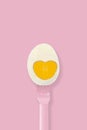 Half boiled egg on a pink fork on pink background, minimal style