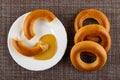 Half of bread ring poured peanut butter in plate, baranka on mat. Top view Royalty Free Stock Photo