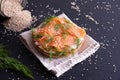 Bun topped with fresh cream, garnished with smoked fish trout and sprinkled with fresh dill and sesame seeds on a napkin